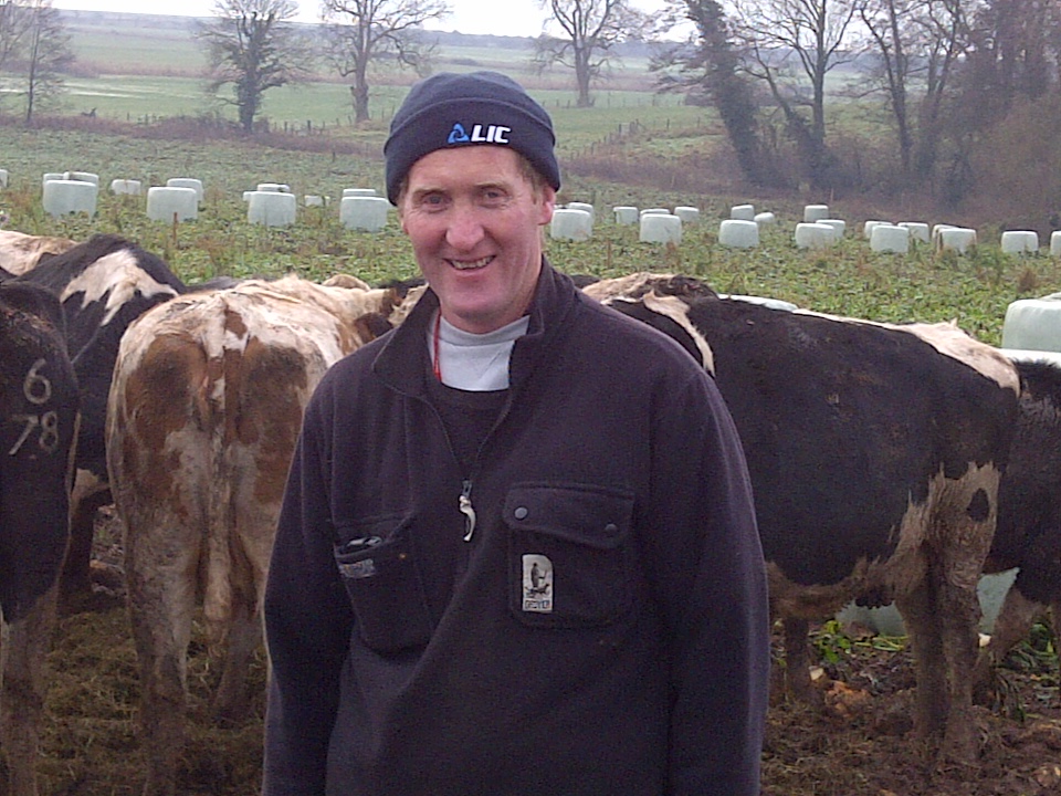 a man smiling in front of a herd of cows